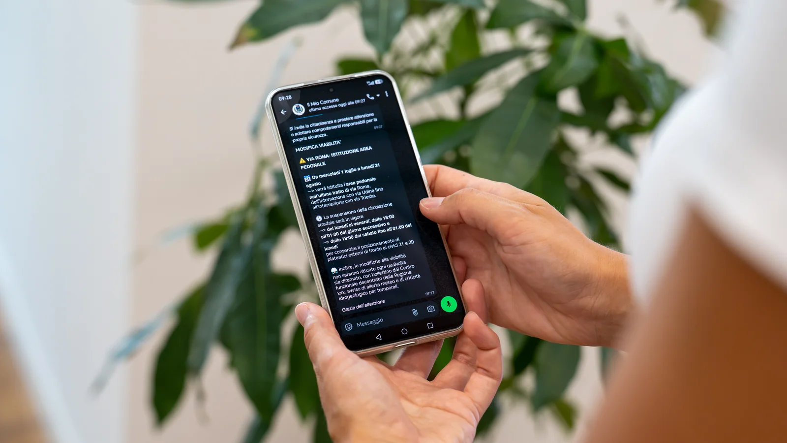 Un cittadino legge sul telefono l'avviso del proprio Comune ricevuto su WhatsApp